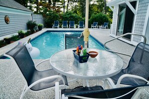 A backyard with a swimming pool, lounge chairs, and a table with bottles and a bowl. - Perfect Vacation House with Private Pool in New Seabury (Mashpee)