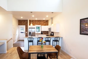 Enjoy meals in this kitchen with a central island, sink, and stainless steel appliances, surrounded by a dining area with a wooden table and chairs.