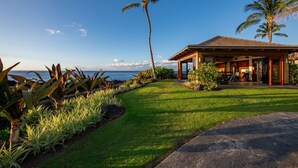 Une propriété située en bord de mer, dotée d’un patio couvert, de palmiers et d’une pelouse bien entretenue.