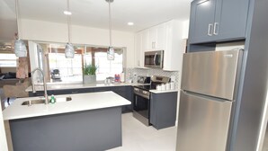 A modern kitchen with a central island, stainless steel appliances, and a view to the outside. - Home on the water w/ pool and dock (Apollo Beach)