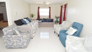 A living room with a sofa set, a blue armchair, and a coffee table. - Home on the water w/ pool and dock (Apollo Beach)