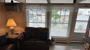 Een gezellige woonkamer met een leren bank, twee kussens met een patroon, een lamp en een decoratieve schelpenvaas.