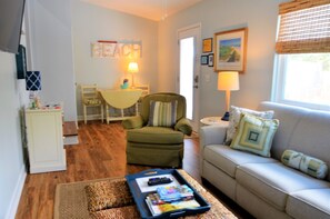 Un salon comprenant un canapé, un fauteuil et une petite table sur laquelle se trouve un plateau avec divers objets.