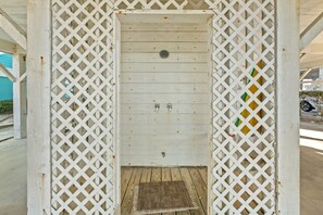 A white wooden door with a metal handle and a small step leading up to it, set within a white lattice structure.