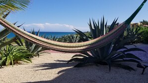 Una hamaca en un jardín con plantas tropicales y vistas al océano.