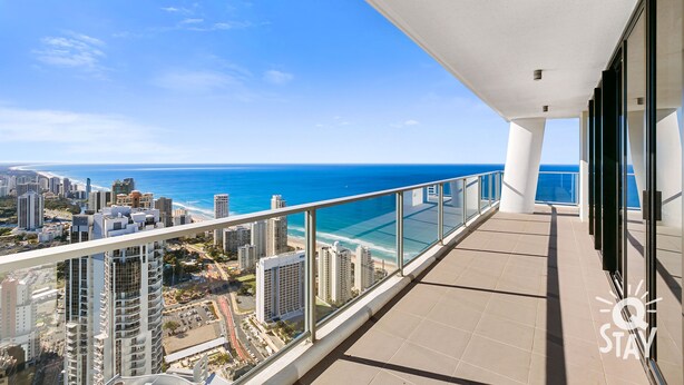Un balcon avec vue sur l’océan et le paysage urbain.