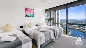 Une chambre d’hôtel moderne avec deux lits, une grande fenêtre donnant sur la ville et un tableau au mur.