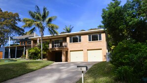 A two-story residential building with a garage, a covered patio, and a well-maintained lawn. - Beach House - direct 2-min access to the beach (Depot Beach)