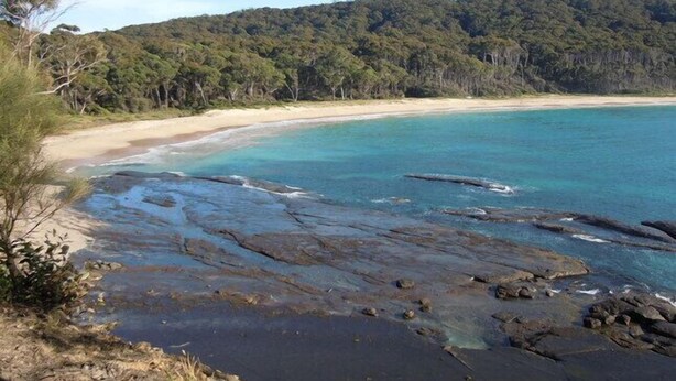 A coastal landscape with a sandy beach, clear turquoise waters, and a forested hill in the background. - Beach House - direct 2-min access to the beach (Depot Beach)