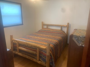 A small, single-bed room with a wooden frame and colorful bedding.