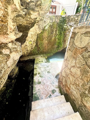 A stone staircase leading down to a pool surrounded by rocky walls.