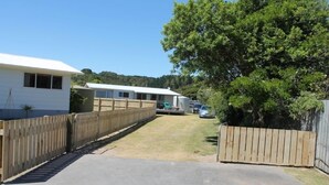 A residential area with a paved driveway leading to a white house with a fenced yard. - Destination Matapouri (Matapouri)