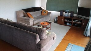 A living room with a sofa, a coffee table, a television, and a sound system. - Destination Matapouri (Matapouri)