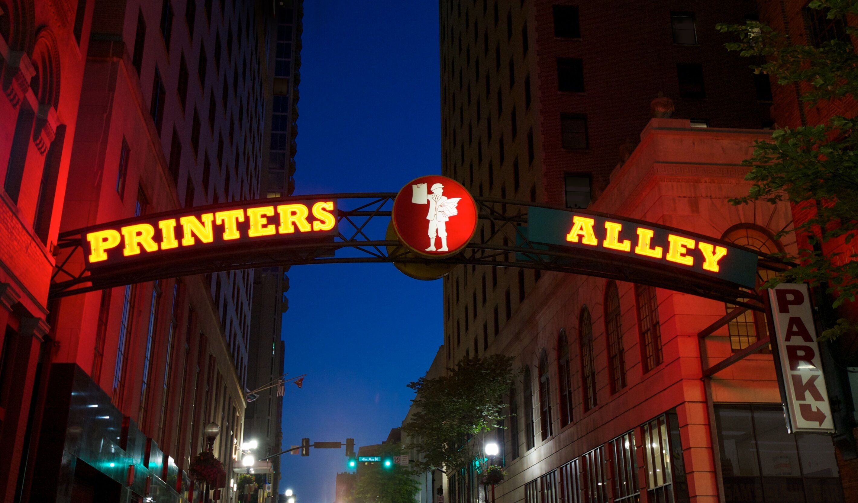 Una señal de calle para Printers Alley, con una señal de alto roja y un símbolo de paso de peatones.