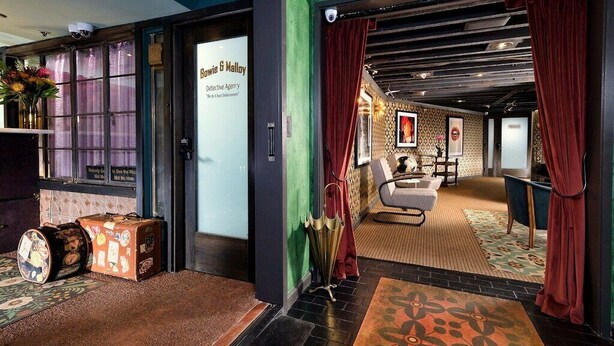 Un hall d’hôtel comprenant un comptoir d’accueil, un espace salon et un tapis à motifs.