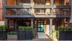 Un edificio a più piani con una porta verde, area salotto esterna e illuminazione decorativa.