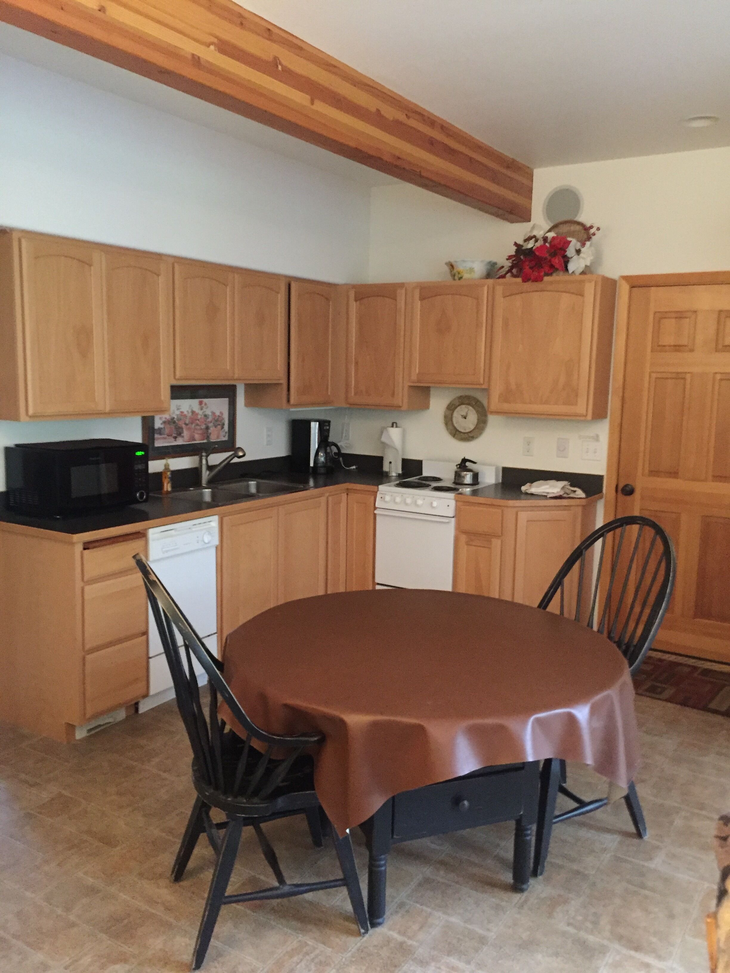A kitchen with wooden cabinets, a microwave, a stove, and a dining table with chairs.