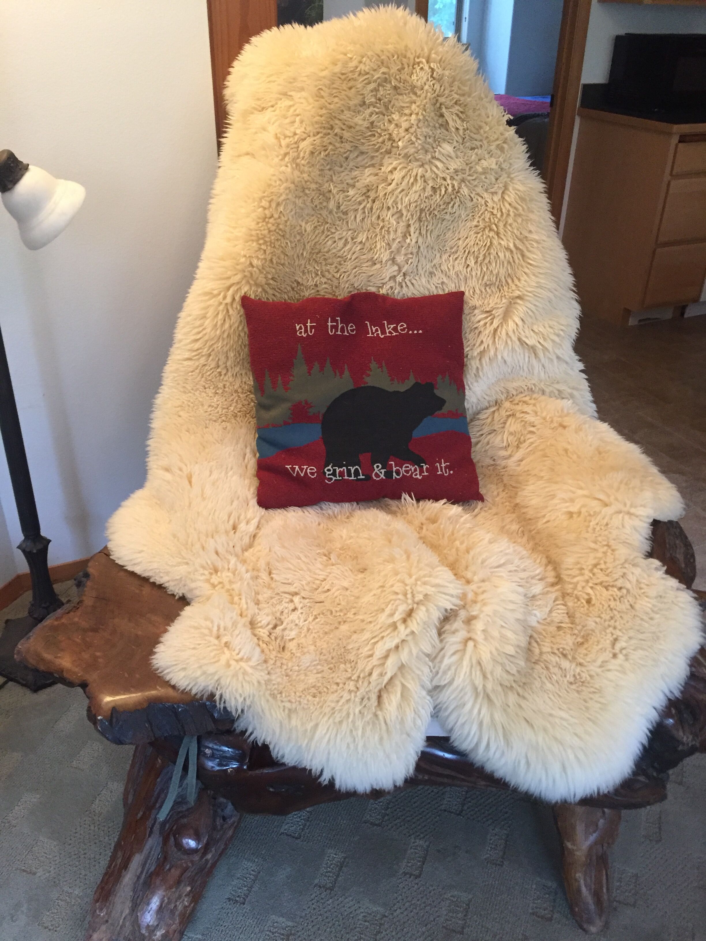 Un sillón mullido con asiento y respaldo afelpados, que incluye un cojín con la silueta de un oso y texto.