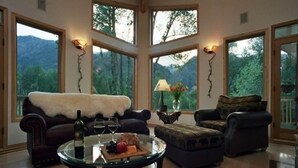 A spacious living room with a large glass table, leather sofas, and a view of a mountainous landscape through large windows. -  Riverdance Lodge: Best Family and Friends private Icicle River Fun Getaway!! (Leavenworth)