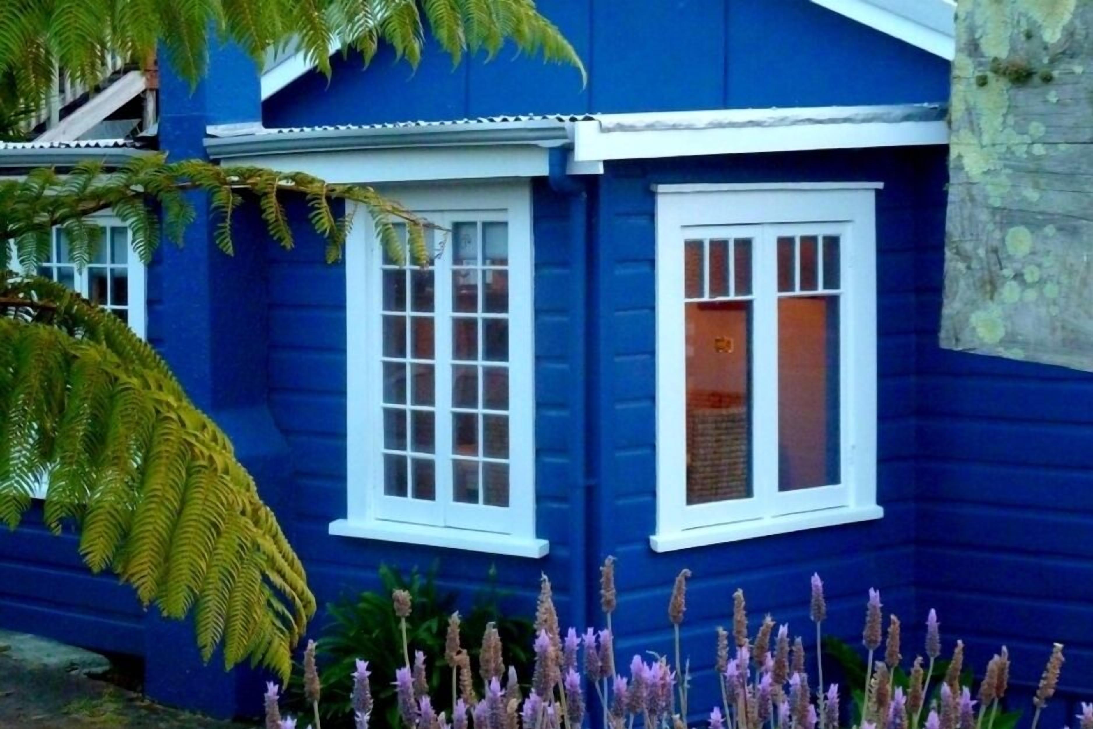 Una casa blu con infissi bianchi e un piccolo portico.