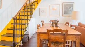 A spiral staircase with yellow steps leading to a dining area with a wooden table and chairs. - Eclectic large living space steps from the the Eifel Tower 2bedrs 2,1/2bathrs (Paris)