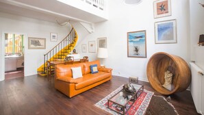 A spacious living room with a wooden staircase, a leather sofa, and a large wooden barrel sculpture. - Eclectic large living space steps from the the Eifel Tower 2bedrs 2,1/2bathrs (Paris)