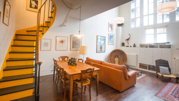 A spacious living area with a wooden staircase, a dining table with chairs, a sofa, and a fireplace. - Eclectic large living space steps from the the Eifel Tower 2bedrs 2,1/2bathrs (Paris)