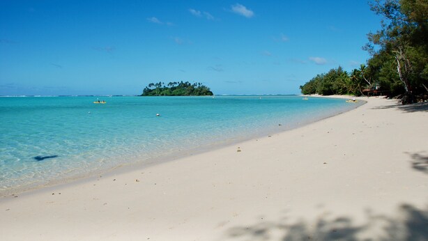A beach with clear turquoise water, a sandy shore, and a small island in the distance. - Mataheres Upstairs Muri (Muri Beach)