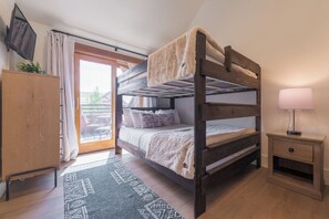 A bunk bed with a blanket, a bedside table with a lamp, a wooden cabinet, and a patterned rug. - Luxury Remodeled 2BR/3BA River Run • Vaulted Ceilings • Washer/Dryer • Sleeps 8 (Keystone)