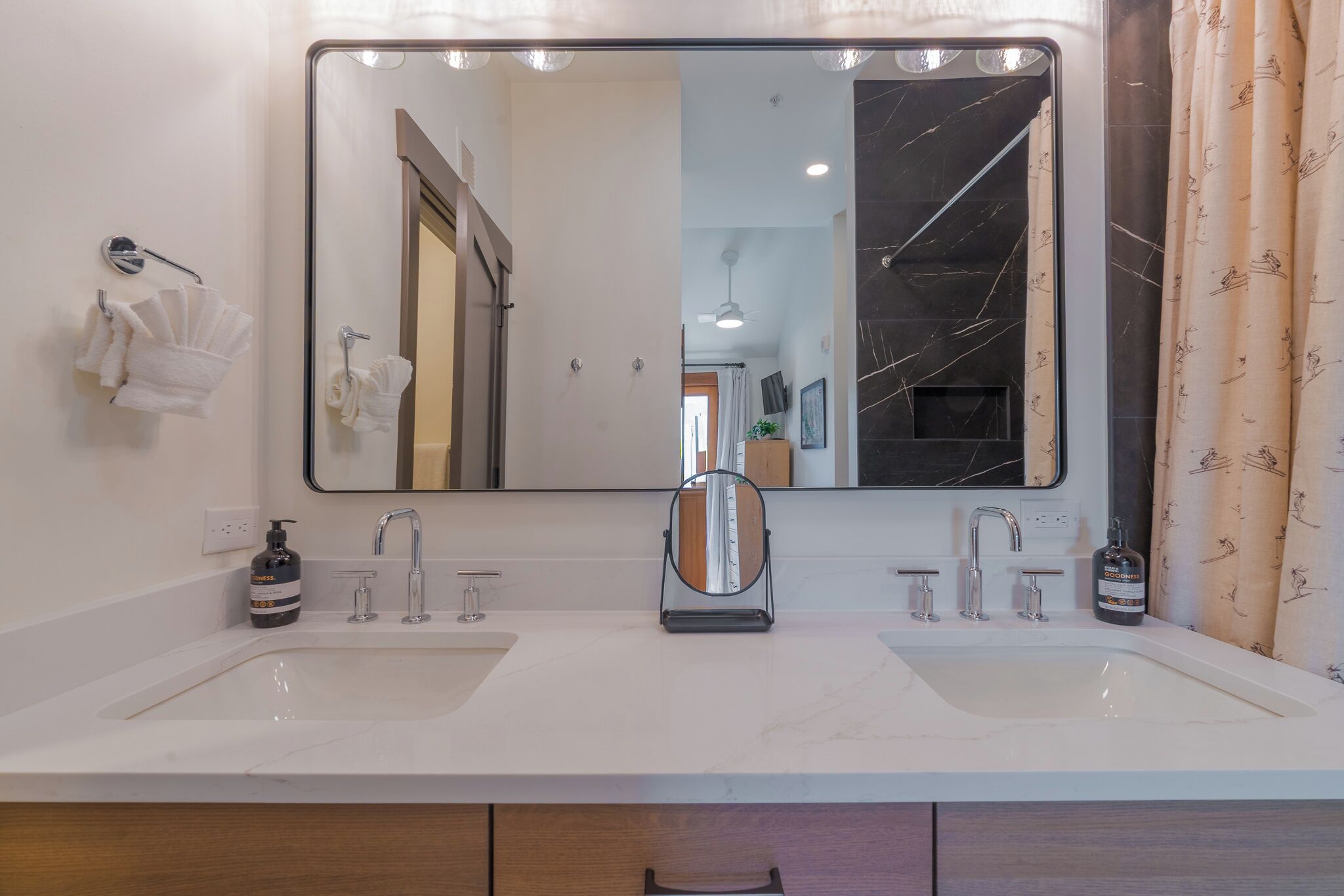A bathroom with two sinks, a large mirror, and a towel rack.
