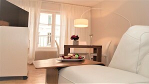 A hotel room with a bed, a small table with a vase of flowers, a chair, and a lamp. - Saint German des-Prés chic and comfortable (Paris)