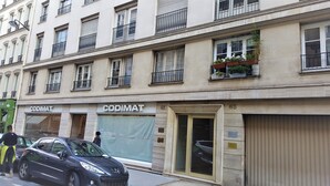 A building with a storefront labeled "CODIMAT" and a closed garage door. - Saint German des-Prés chic and comfortable (Paris)