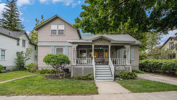 A two-story house with a front porch, a small front yard, and a visible staircase leading to the entrance.