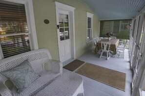 A covered porch with wicker furniture, a door, and a table with chairs. - Top Performer! Quintessential historic cottage (Rehoboth Beach)