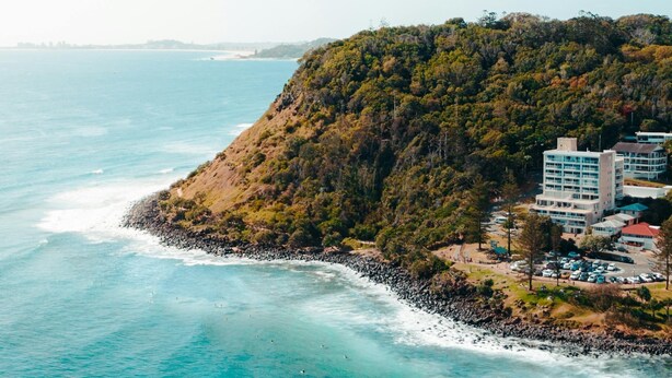 A coastal area with a beach, rocky shoreline, and buildings with multiple floors. - Burleigh Beach Pad 100m from beach - stunning (Burleigh Heads)