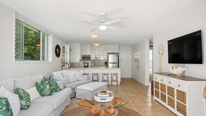 A modern living room with a sofa, coffee table, and TV. - Burleigh Beach Pad 100m from beach - stunning (Burleigh Heads)