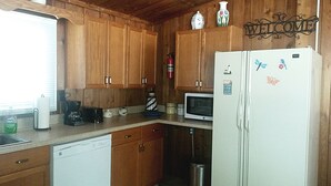 A kitchen with wooden cabinets, a white refrigerator, a microwave, and a coffee maker.
