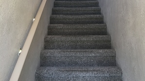 Eine Treppe mit Handlauf, einer Wandleuchte und einem Wandbild.