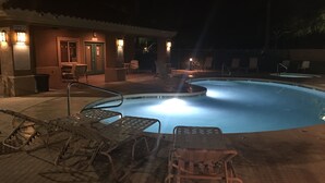 Ein Poolbereich bei Nacht mit Liegestühlen und einem Gebäude, an dem ein Schild mit der Aufschrift 'Smoke Free' angebracht ist.