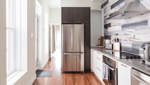A modern kitchen with a stainless steel refrigerator, a built-in oven, and a gas stove. - MTLVR #12 | Central, Kid-Friendly, Metro 3 min (Montreal)