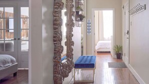 A hallway with a large ornate mirror, a blue bench, and a door leading to a bedroom. - MTLVR #12 | Central, Kid-Friendly, Metro 3 min (Montreal)