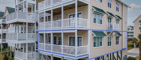 A multi-story residential building with balconies and a covered porch area.