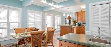 A kitchen with a dining area, featuring a table with chairs, a kitchen island, and wooden cabinets.