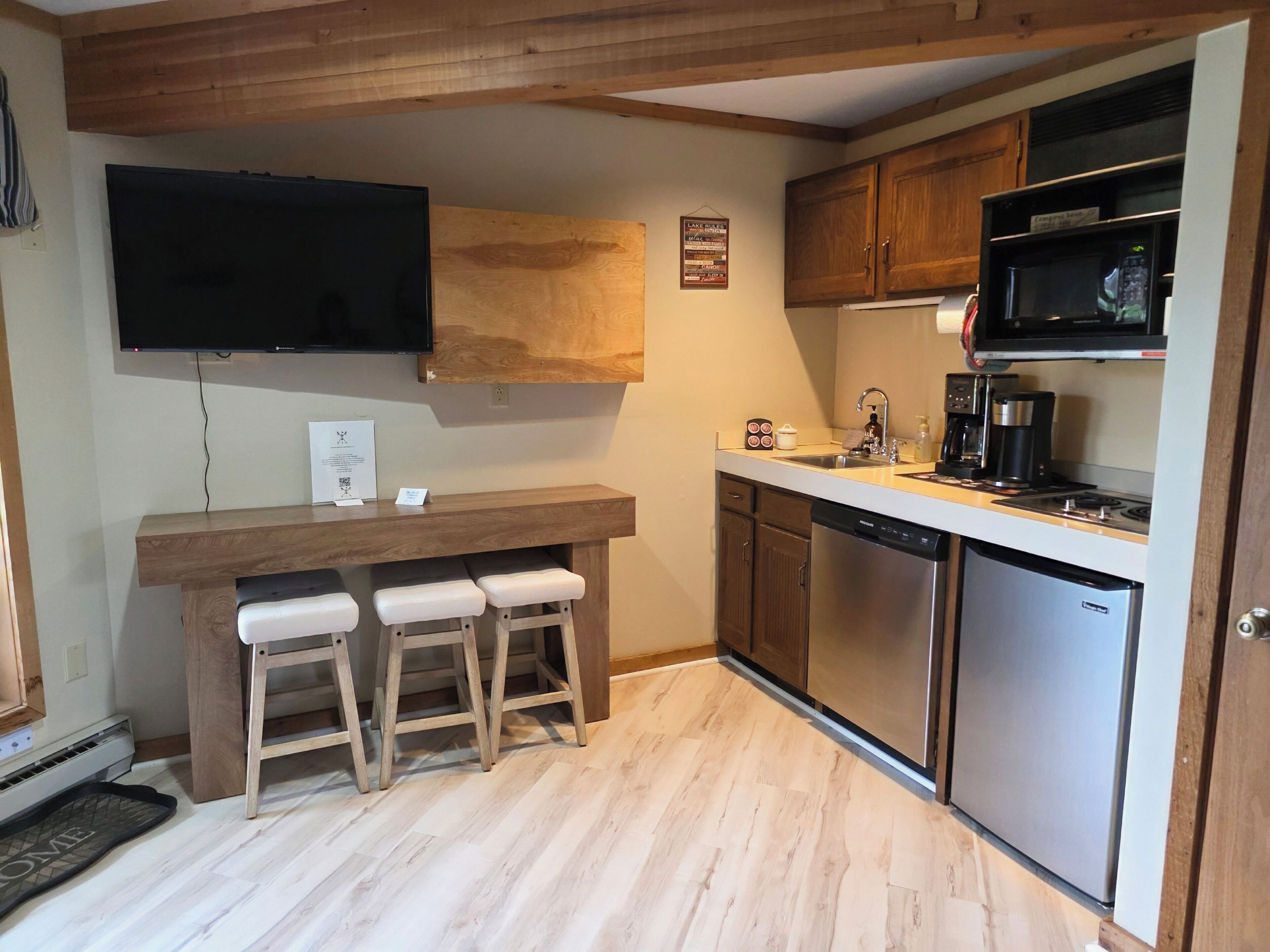 A compact kitchen with wooden cabinets, a built-in microwave, a coffee maker, and a dishwasher.