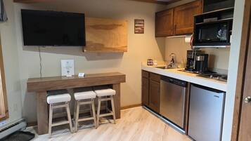 A compact kitchen with wooden cabinets, a built-in microwave, a coffee maker, and a dishwasher.