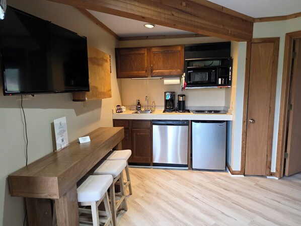 A compact kitchen with wooden cabinets, a microwave, a coffee maker, and a dishwasher. - Schuss MOUNTAIN VIEW! golf course Close to lakes pool Temperpedic mattress (Mancelona)