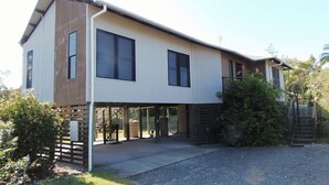A modern two-story house with large windows, a covered porch, and a gravel driveway.