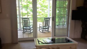 Een kamer met een schuifglazen deur die uitkomt op een terras met twee schommelstoelen.