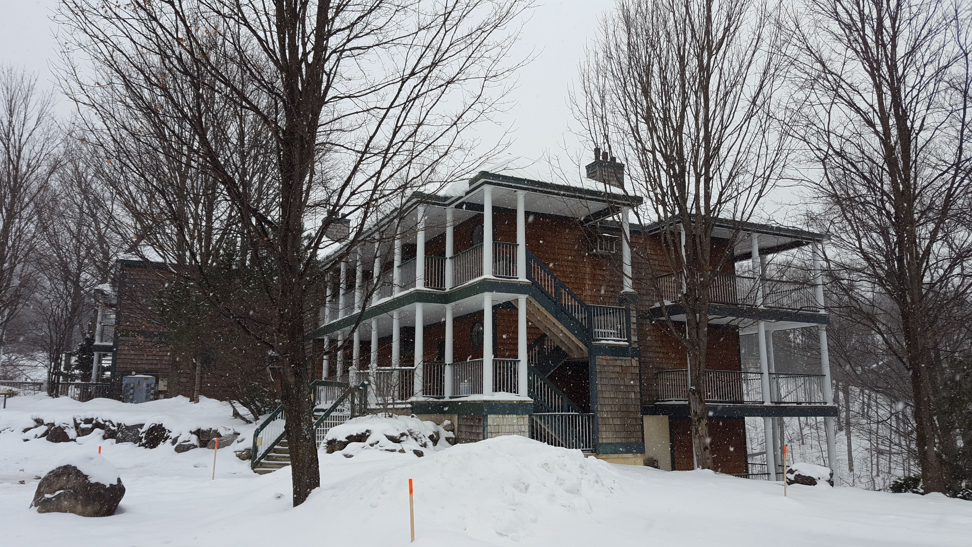 A multi-story building with a balcony, surrounded by snow-covered trees.