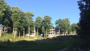 Een meerlaags gebouw met balkons, omgeven door bomen en een gazon.